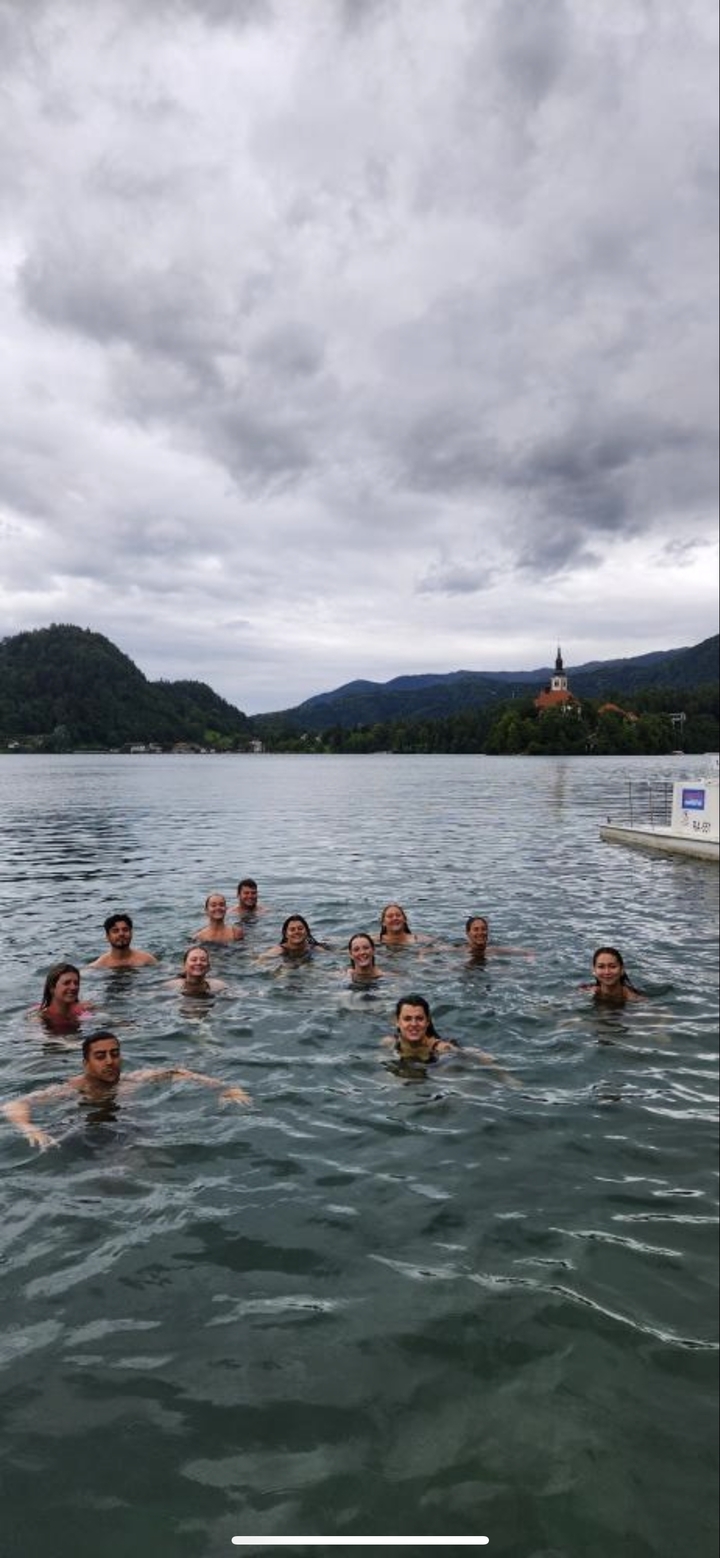 Groupe de personnes nageant dans un lac avec une église sur une île.
