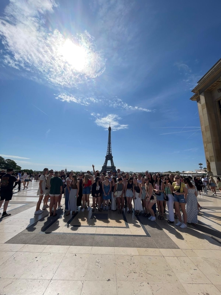 Photo de groupe devant la tour Eiffel sous un ciel ensoleillé.