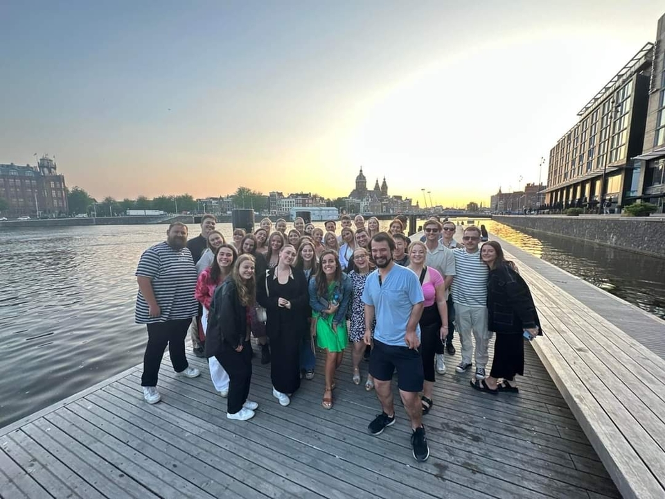 Photo de groupe au bord de l'eau au coucher du soleil avec Amsterdam en arrière-plan.