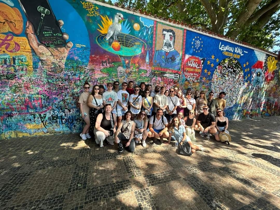 Groupe nombreux devant un mur de graffitis coloré à Prague.
