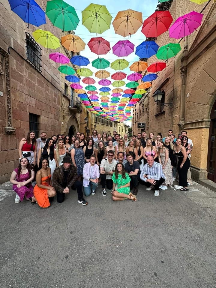 Grand groupe sous des parapluies colorés dans une rue charmante.