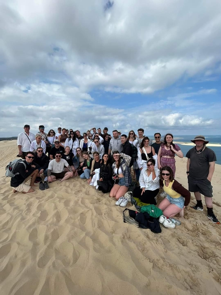 Grand groupe sur des dunes de sable avec la mer bleue en arrière-plan.