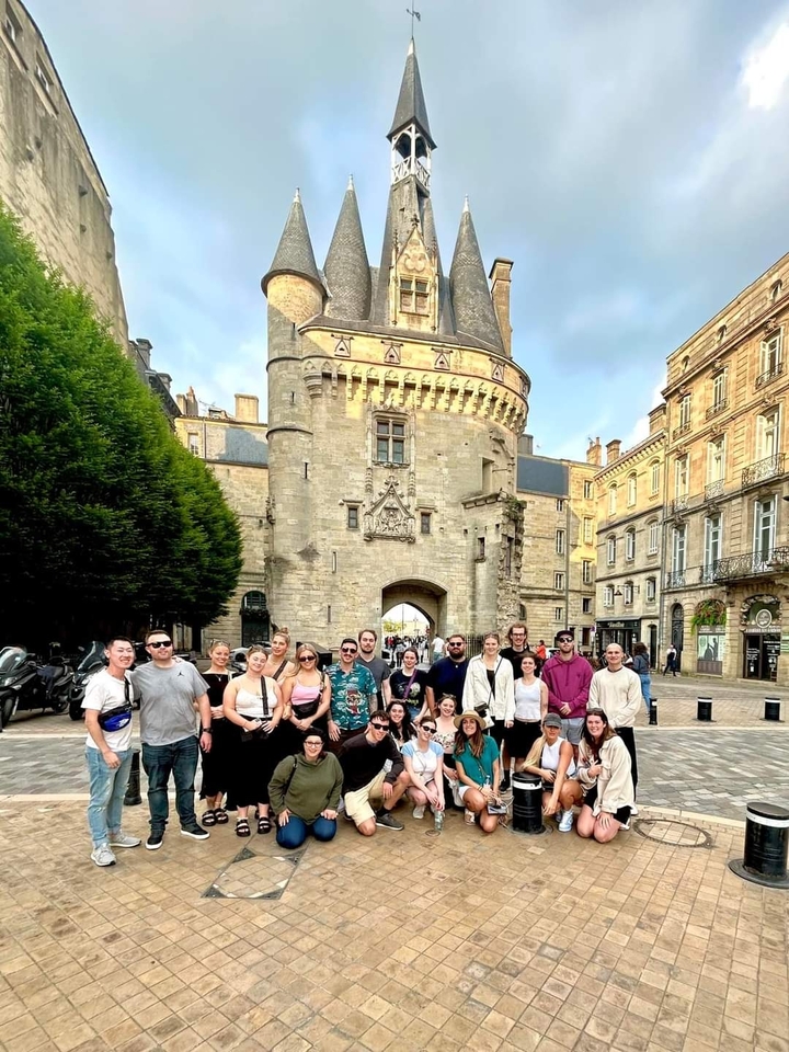 Groupe posant près d'une porte historique à Bordeaux.