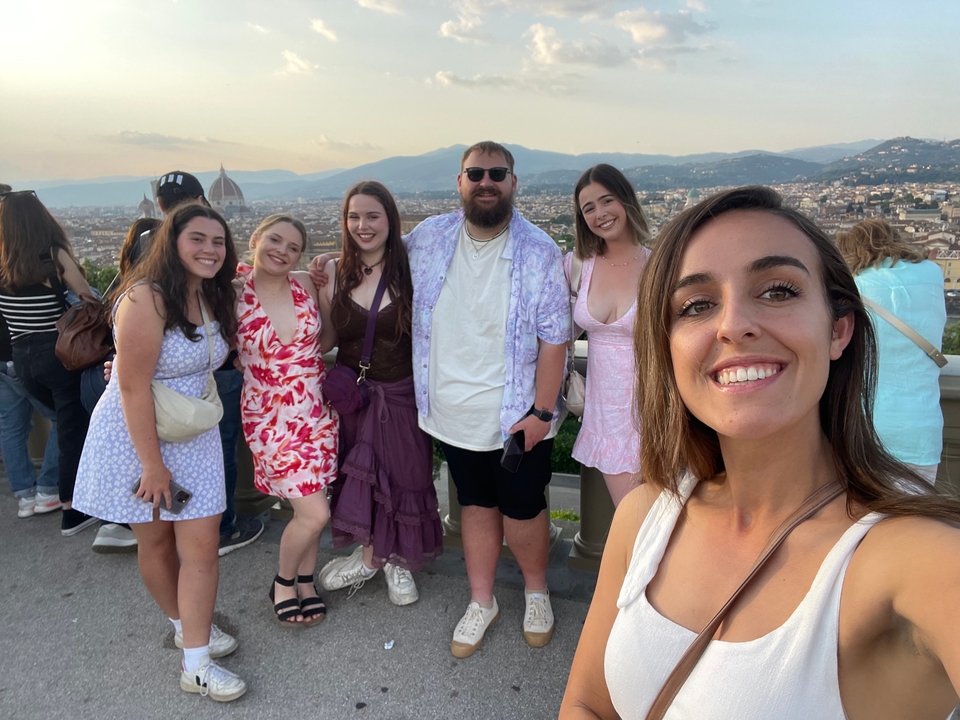 Groupe de jeunes adultes souriants avec un paysage urbain en arrière-plan.