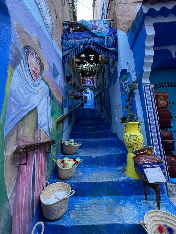 Escalier coloré décoré de fresques et de pots colorés.