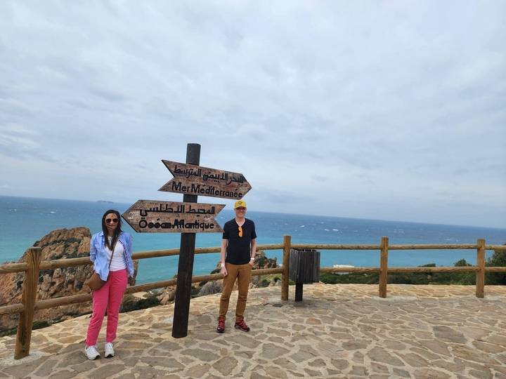 Deux personnes près d'une balustrade en bois surplombant la mer.