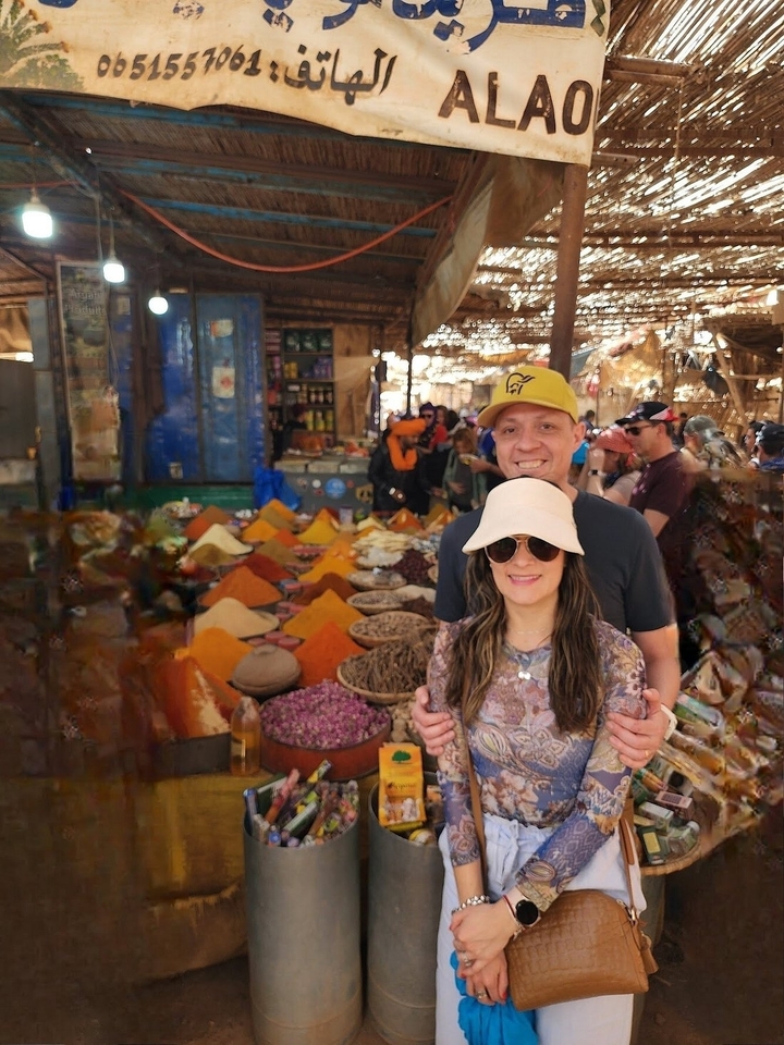 Couple dans un marché entouré d'épices colorées.