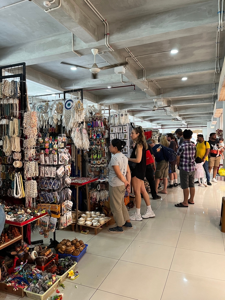 Des acheteurs parcourant un marché couvert d'artisanat et de souvenirs bondé.