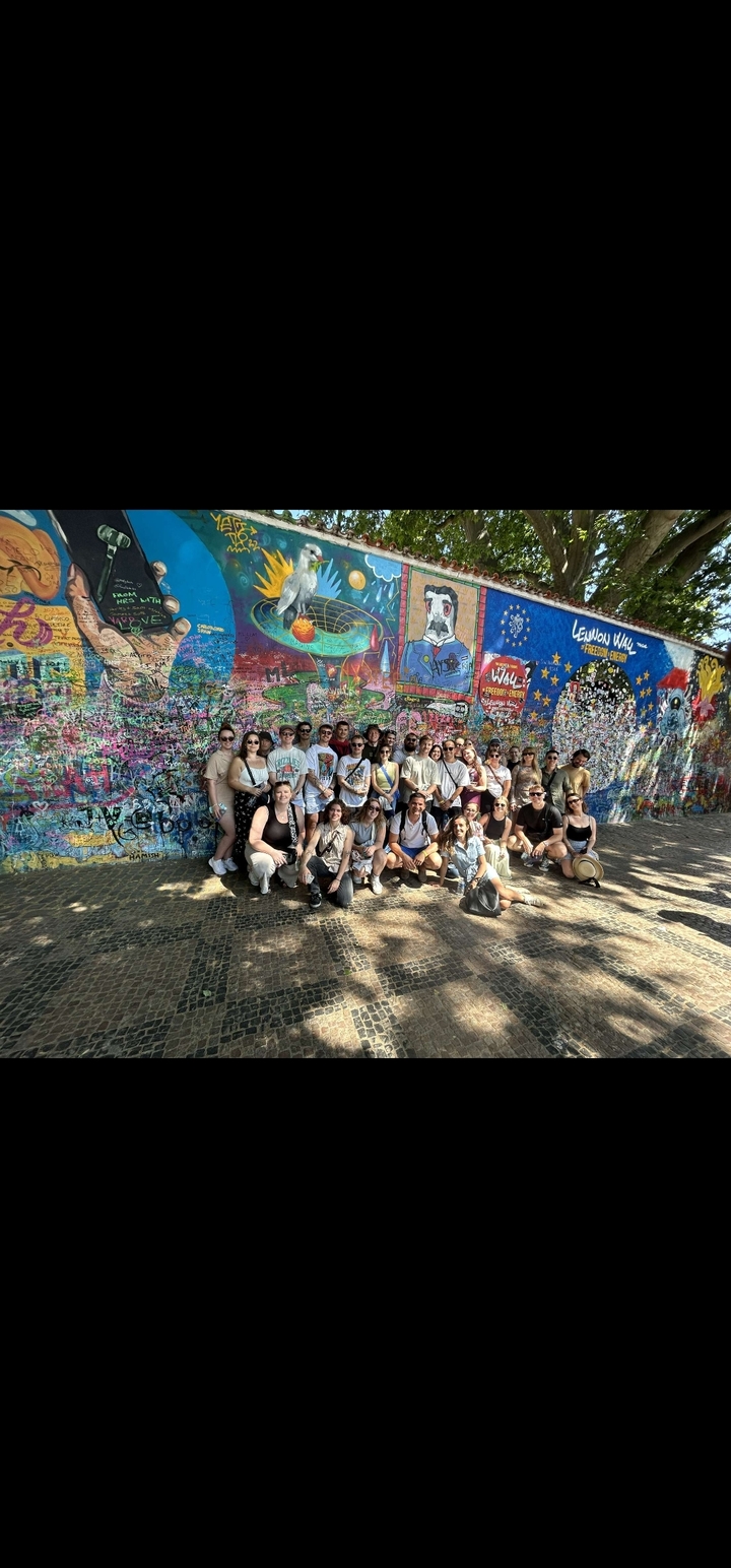 Un grand groupe de personnes posant devant un mur de graffitis coloré.