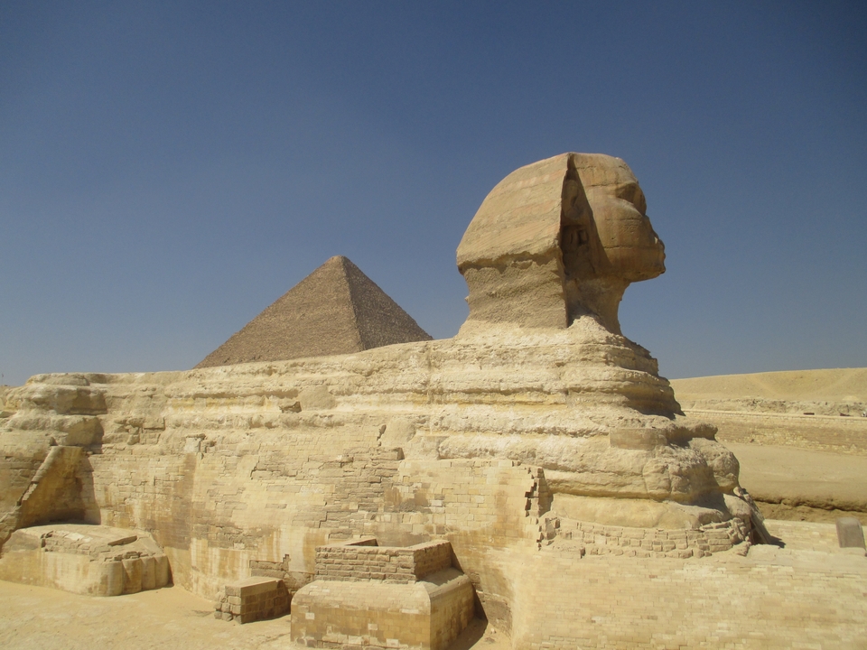 Statue de sphinx avec pyramide en arrière-plan.