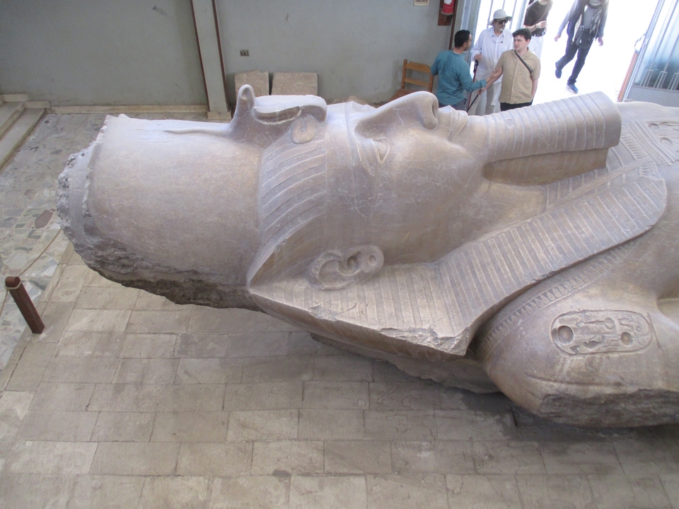 Gros plan d'une grande statue antique d'un pharaon couchée sur le dos.