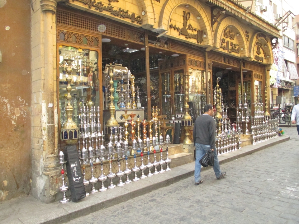 Vue de rue d'un magasin vendant des narguilés avec une personne qui passe.