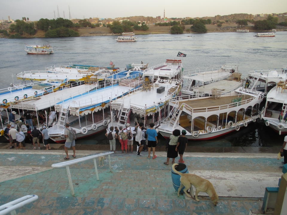 Groupe de bateaux amarrés à une rive avec des personnes qui embarquent.