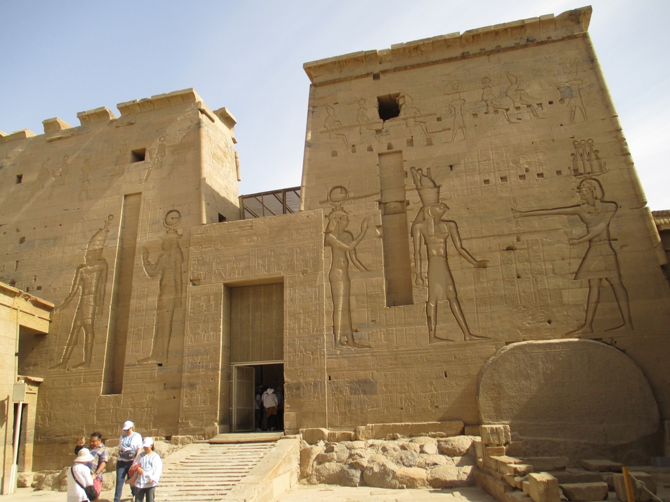 Temple égyptien antique avec hiéroglyphes et des gens qui explorent.