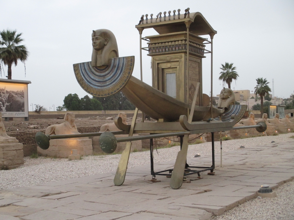 Statue de bateau égyptien antique avec artefacts environnants.