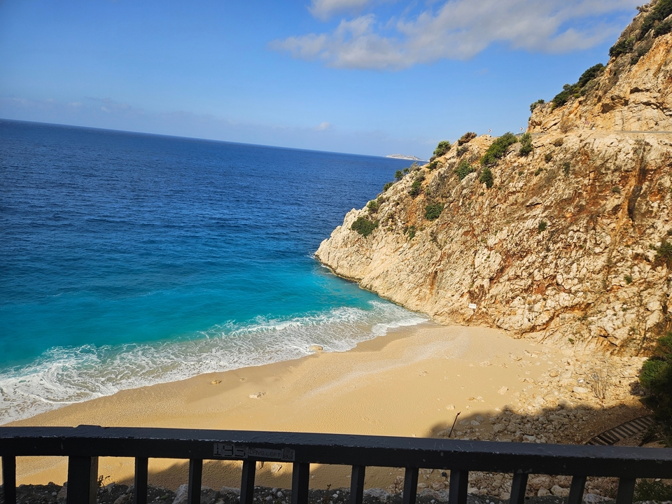 Plage avec une eau bleue claire et un rivage sablonneux.