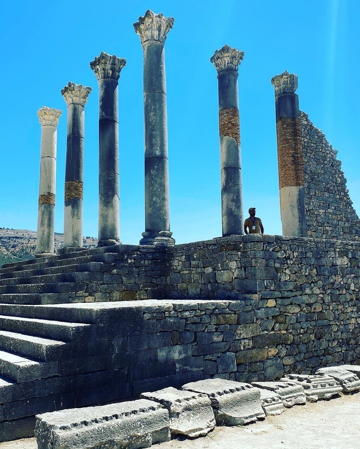 Personne debout près de ruines antiques avec des colonnes.