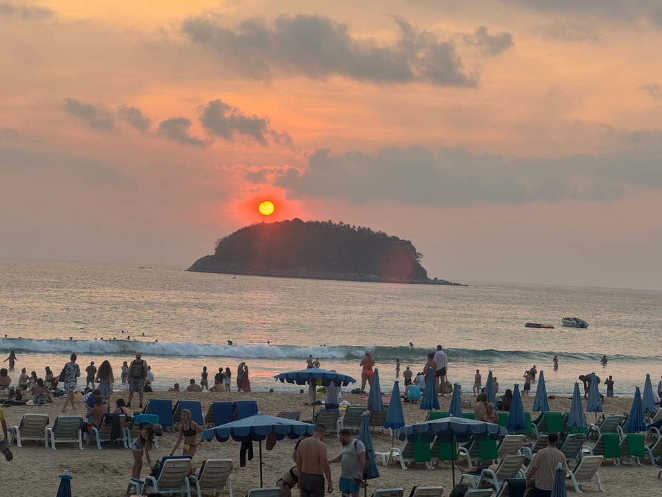 Coucher de soleil sur une plage avec beaucoup de monde.