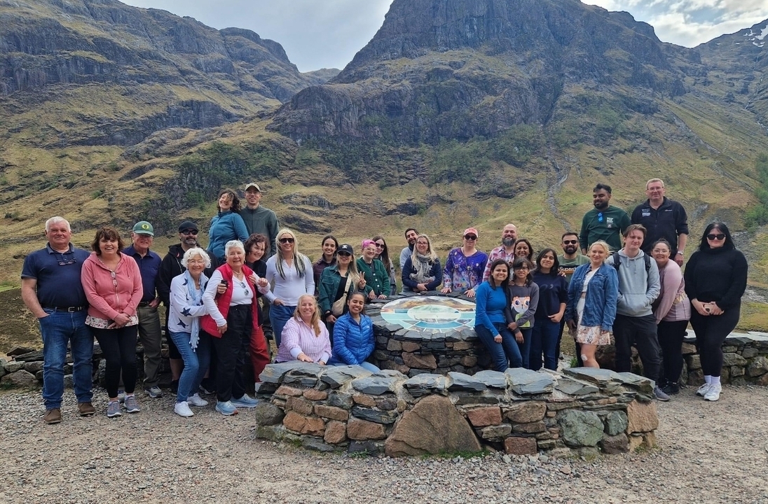 Group of people posing in front of a mountain range.