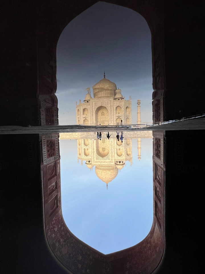 Reflet du Taj Mahal dans l'eau avec des personnes debout.