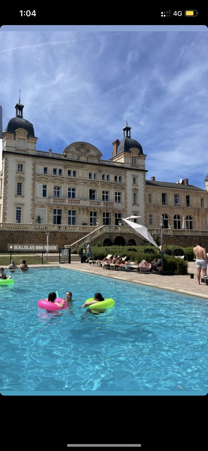 Des gens qui se détendent au bord d'une piscine dans une grande villa.