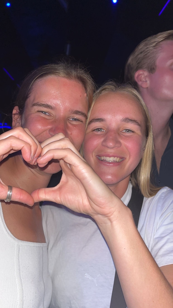 Deux personnes faisant des formes de cœur avec leurs mains à une fête.