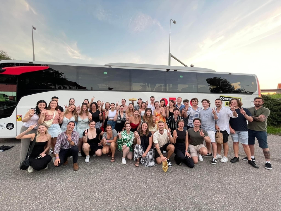 Grand groupe posant devant un autocar de tourisme.