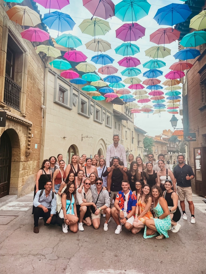 Un grand groupe de personnes posant sous des parapluies colorés dans une rue.