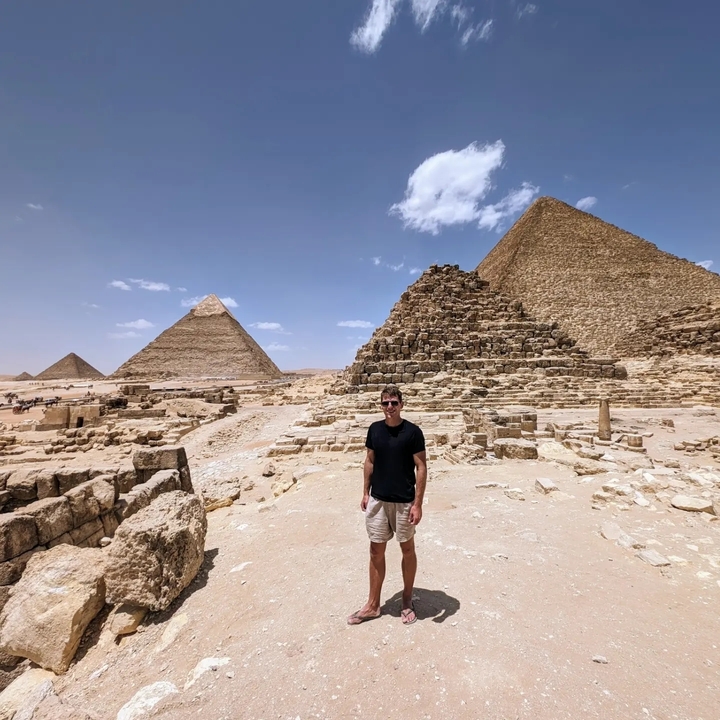 Homme debout devant les pyramides de Gizeh.