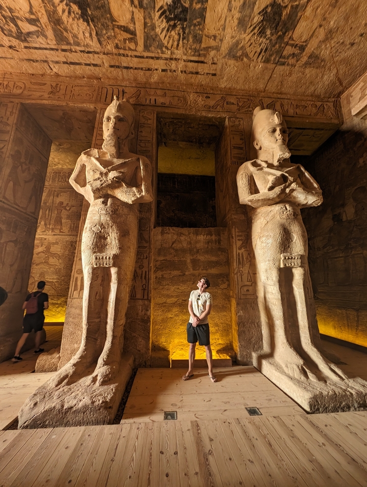 Personne debout entre deux grandes statues à l'intérieur d'un temple.