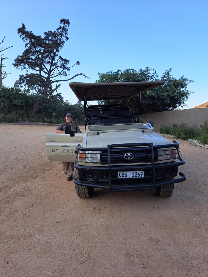 Personne à côté d'un véhicule de safari dans une réserve.