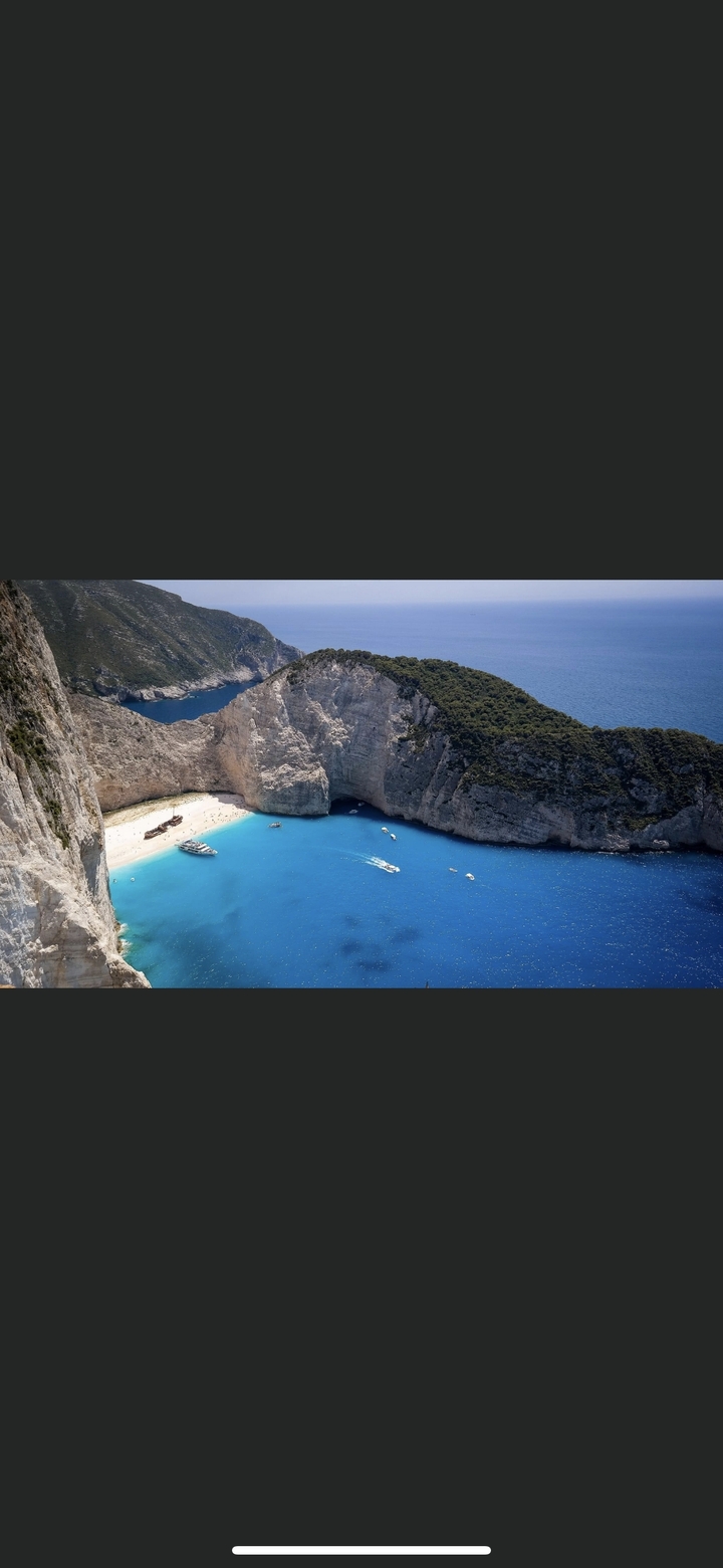 Vue aérienne d'une crique avec une eau bleue claire et des falaises blanches.