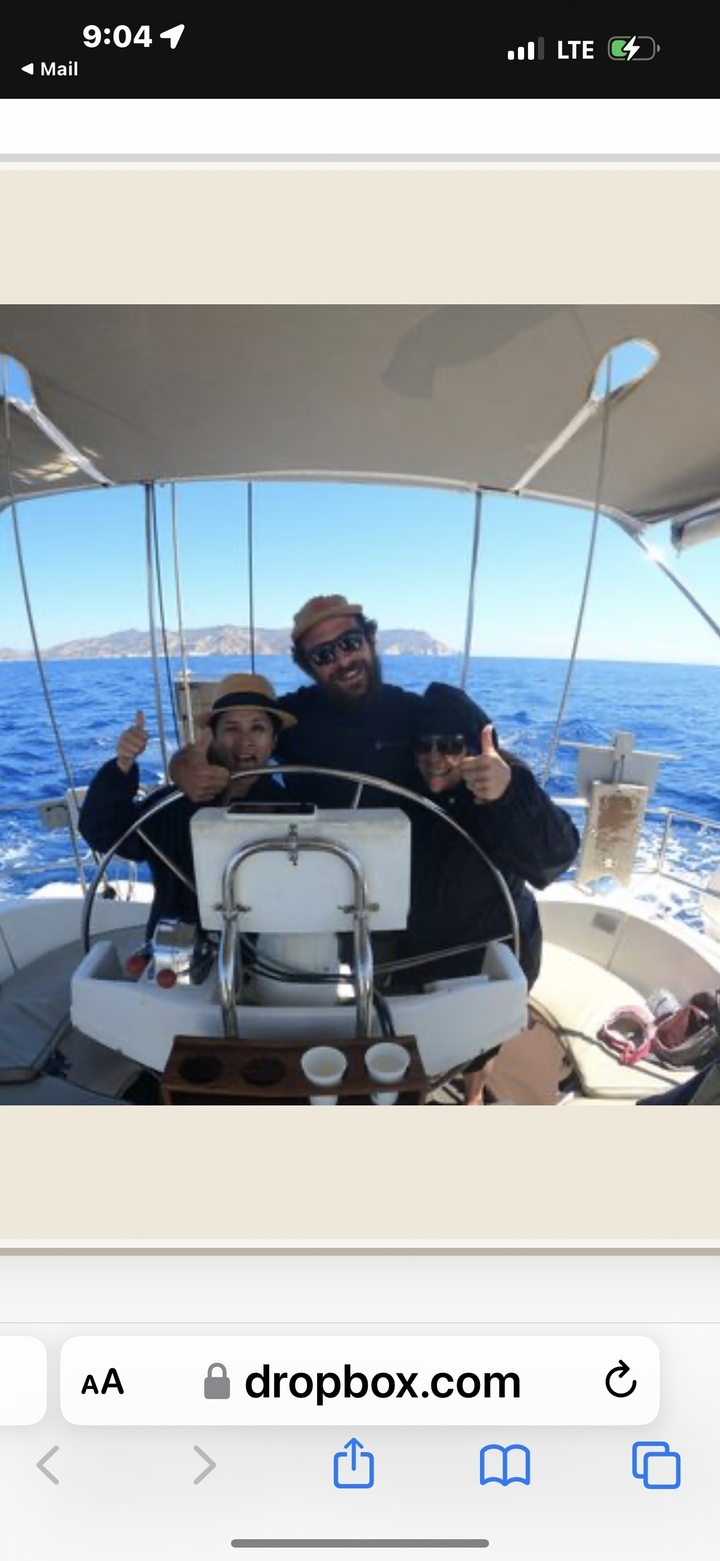 Trois personnes sur un voilier, souriantes et faisant un pouce en l'air.
