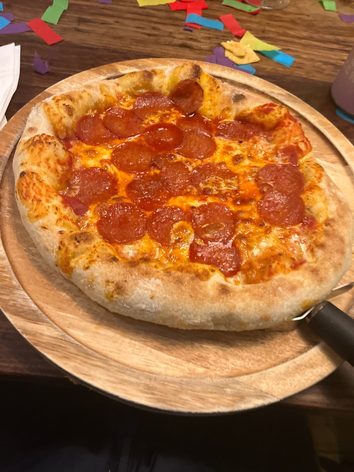 Pepperoni pizza on a wooden board.