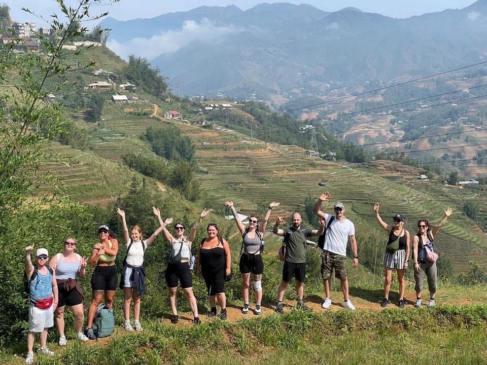 Groupe de randonneurs posant devant des collines en terrasses.