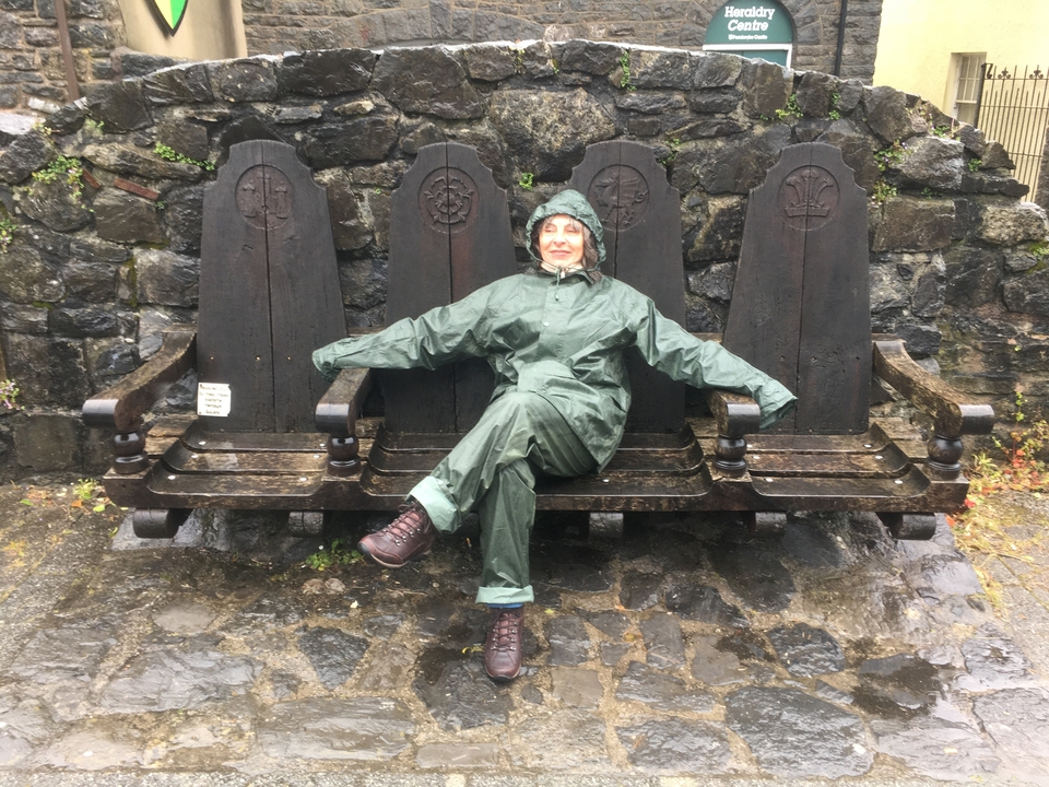 Personne en imperméable vert assise sur un grand banc.