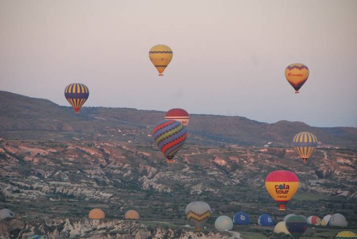 Montgolfières flottant au-dessus d'une vallée pittoresque au lever du soleil.