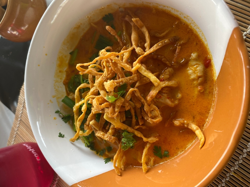 Gros plan d'une soupe de nouilles crémeuse avec des garnitures frites.