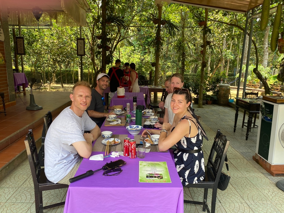 Groupe de personnes qui dînent à l'extérieur à une table.