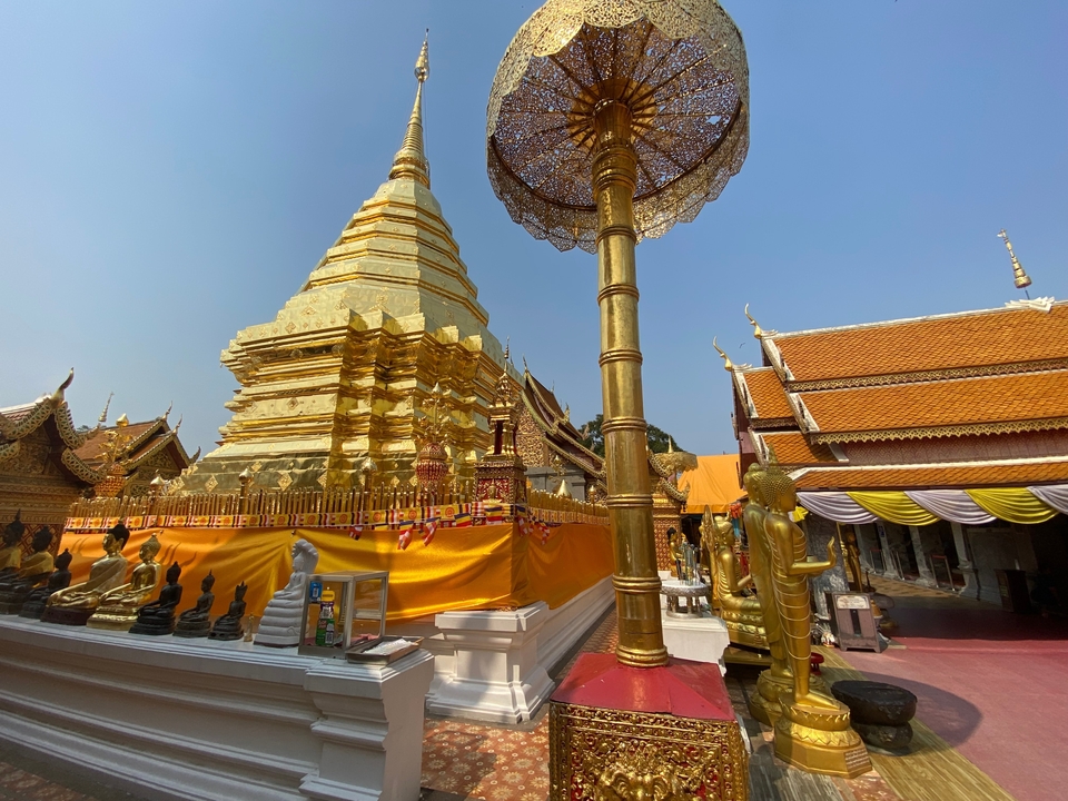 Temple bouddhiste avec stupa doré et statues environnantes.