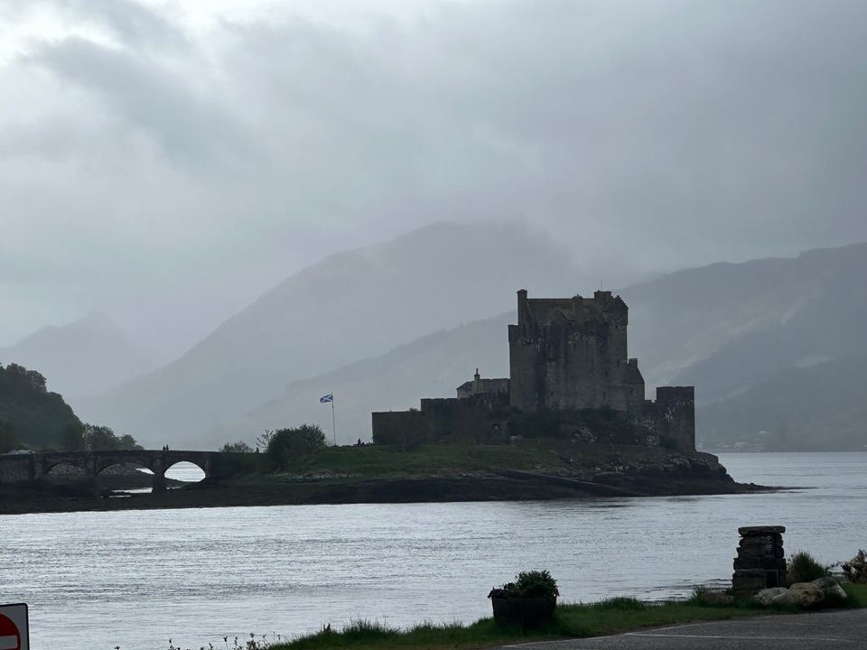 Castle on an island under a cloudy sky, with a bridge connecting it to the mainland.