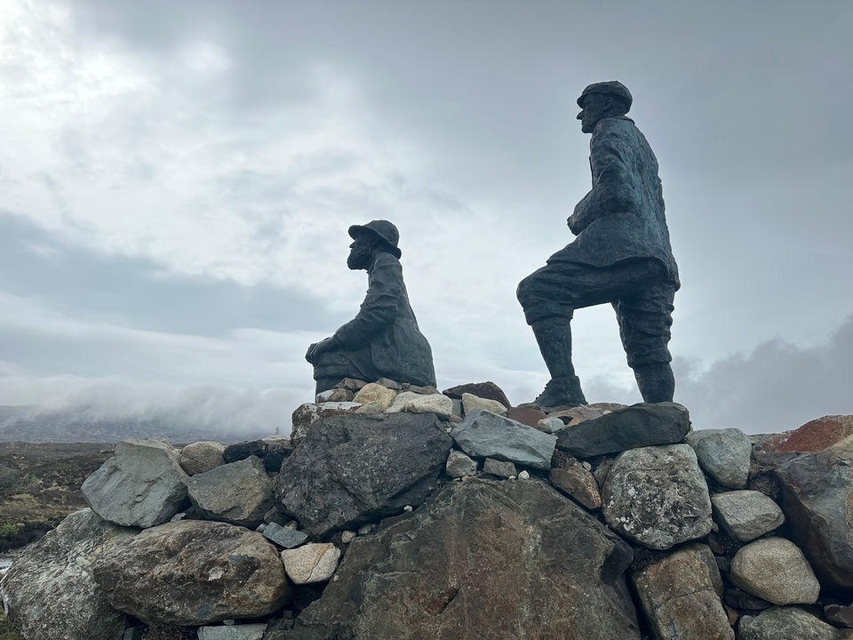 Statues of two explorers overlooking a rocky landscape.