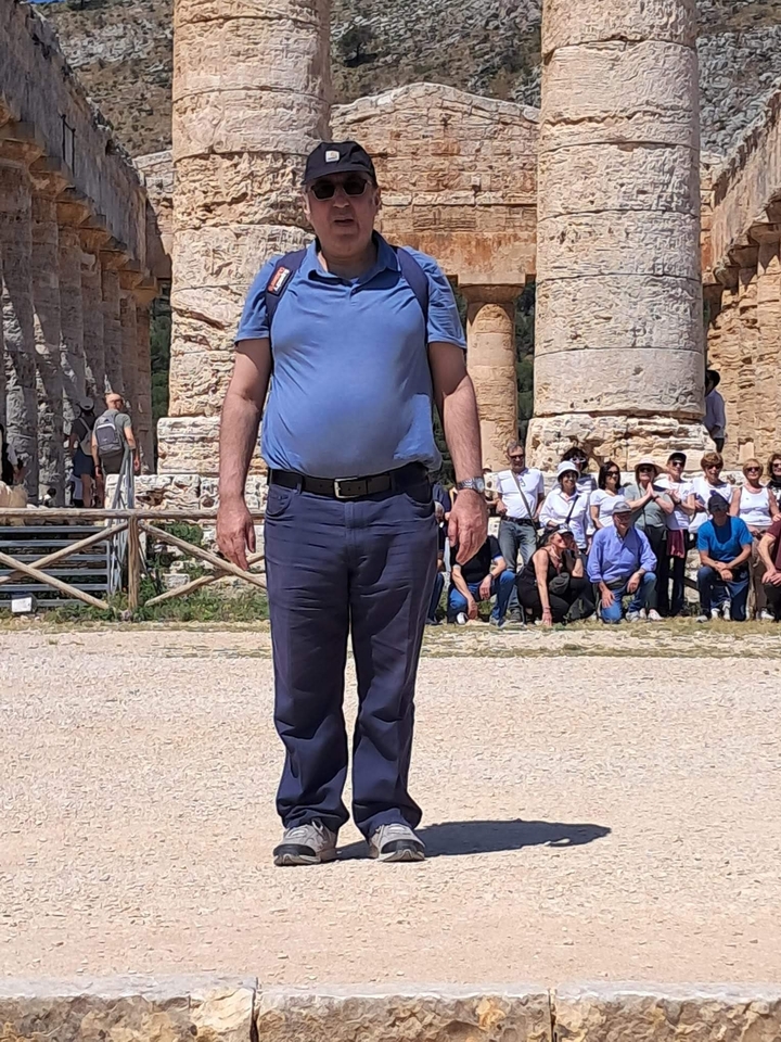 Homme posant avec les ruines d'un temple antique à Ségeste.