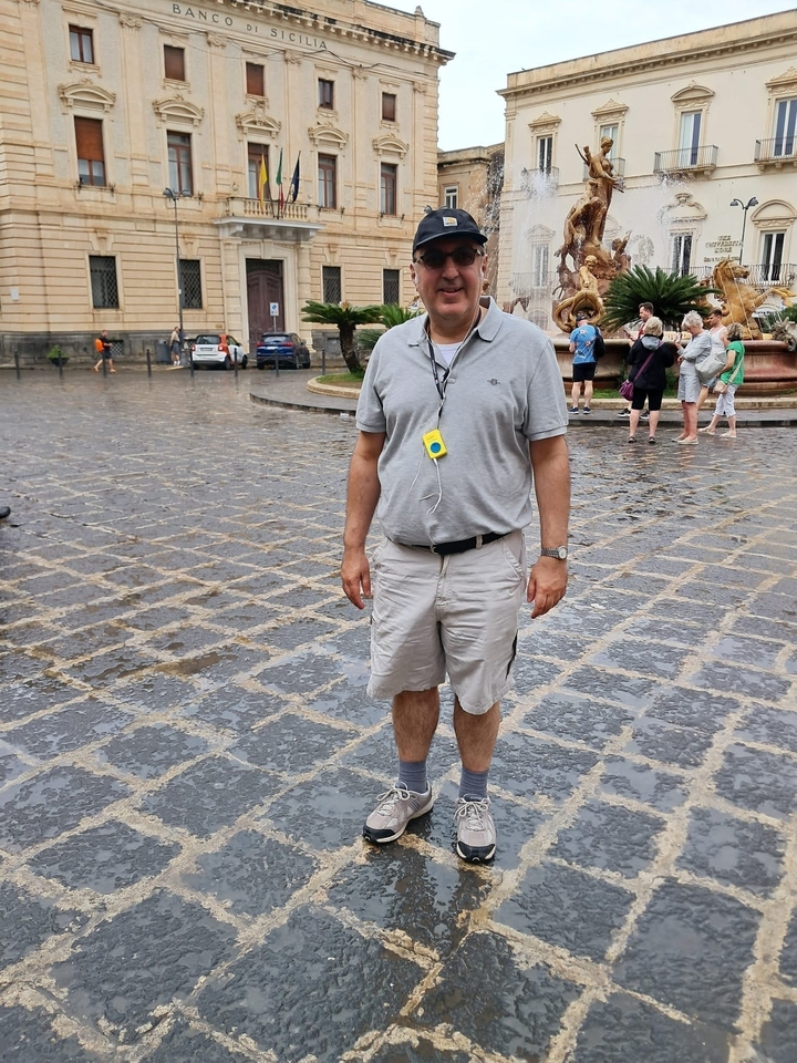 Homme posant sur une place de ville mouillée.