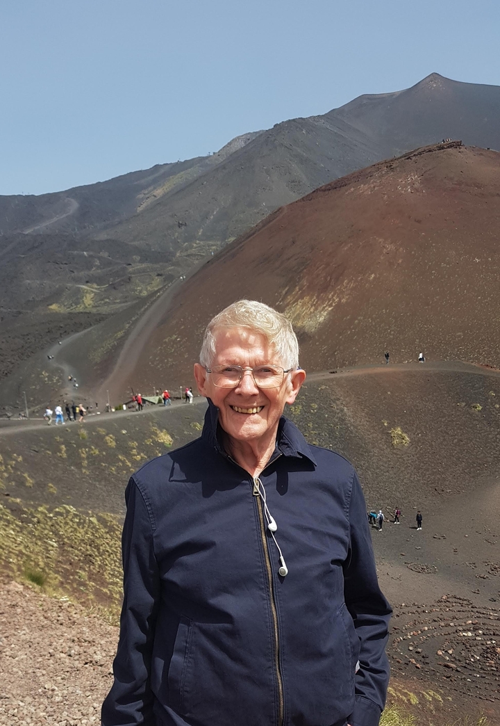 Homme âgé posant sur le terrain du mont Etna.