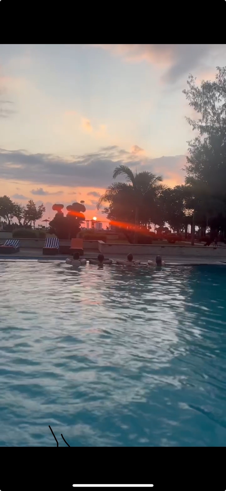 Silhouettes dans une piscine regardant le coucher de soleil.