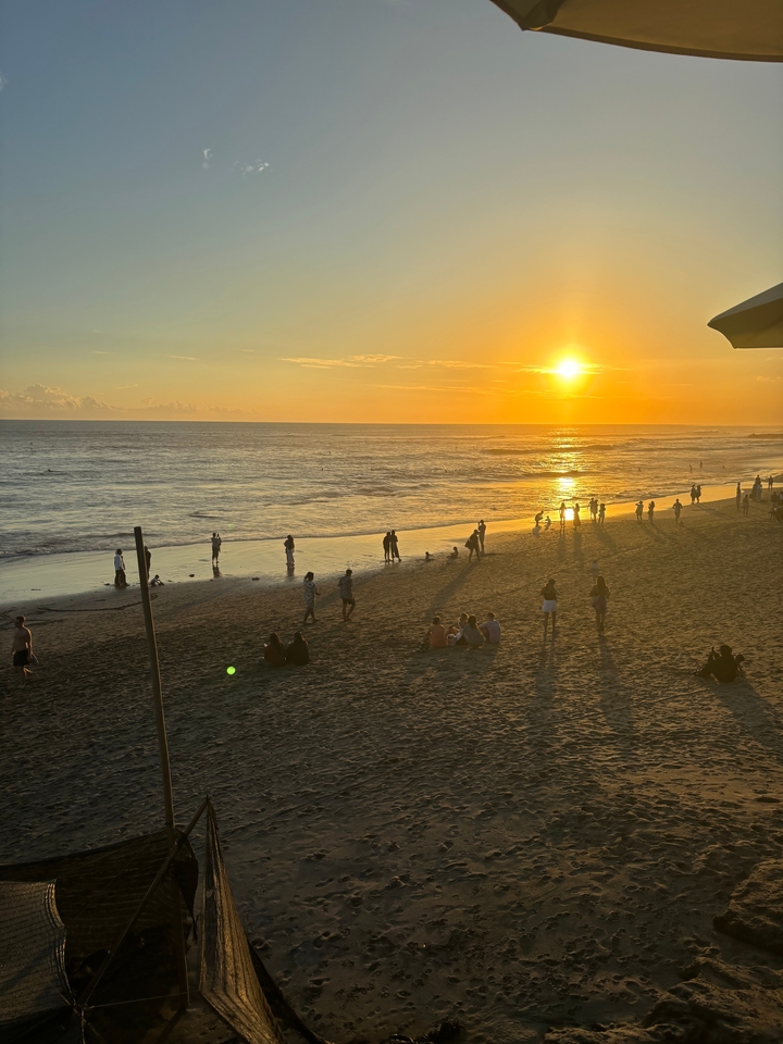 Des gens profitant d'un coucher de soleil éclatant sur la plage.