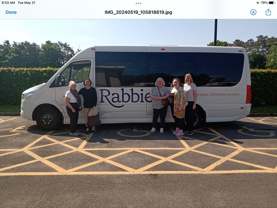 Groupe de personnes debout devant un bus touristique blanc avec le texte 'Rabbie's' dessus.