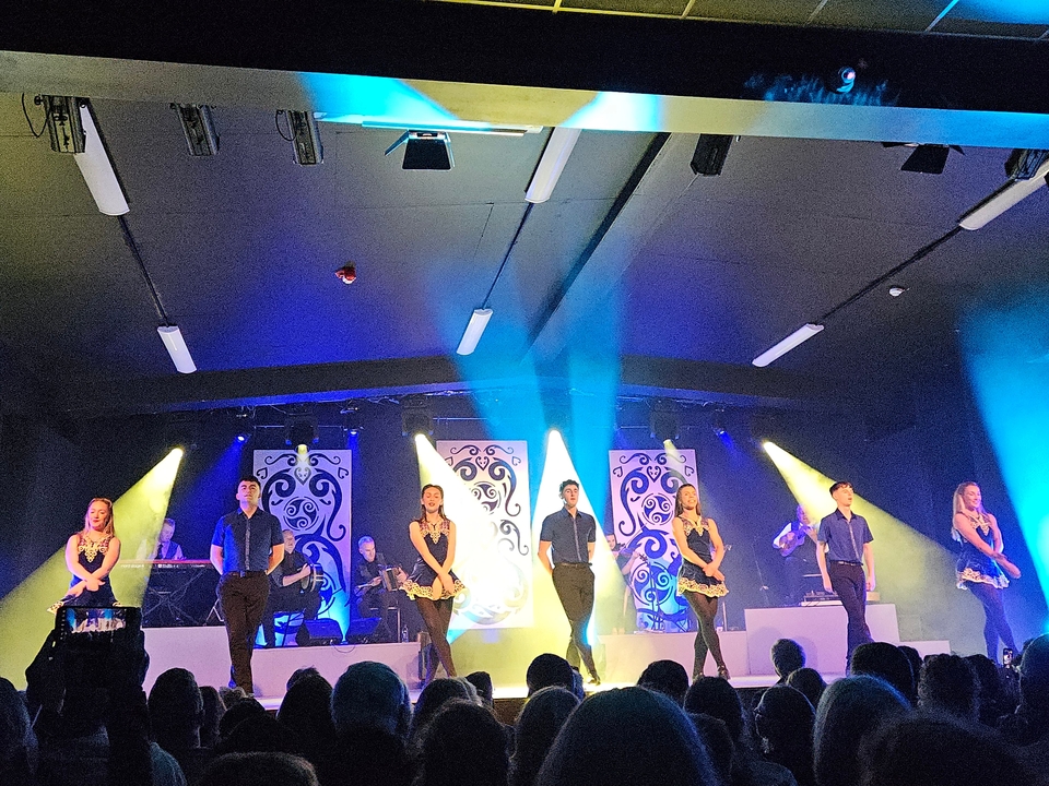 A dance performance on stage with colorful lights.