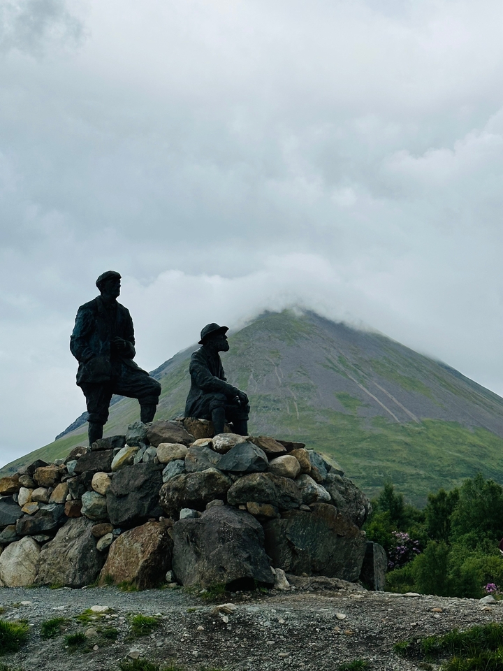 Two statues with a mountain in the background.
